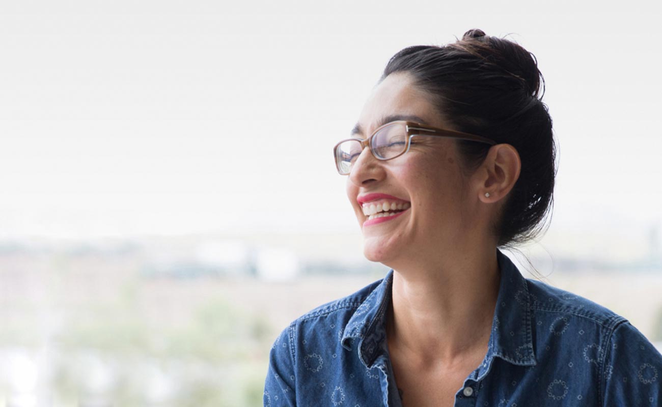 Headshot of woman wearing glasses laughing.