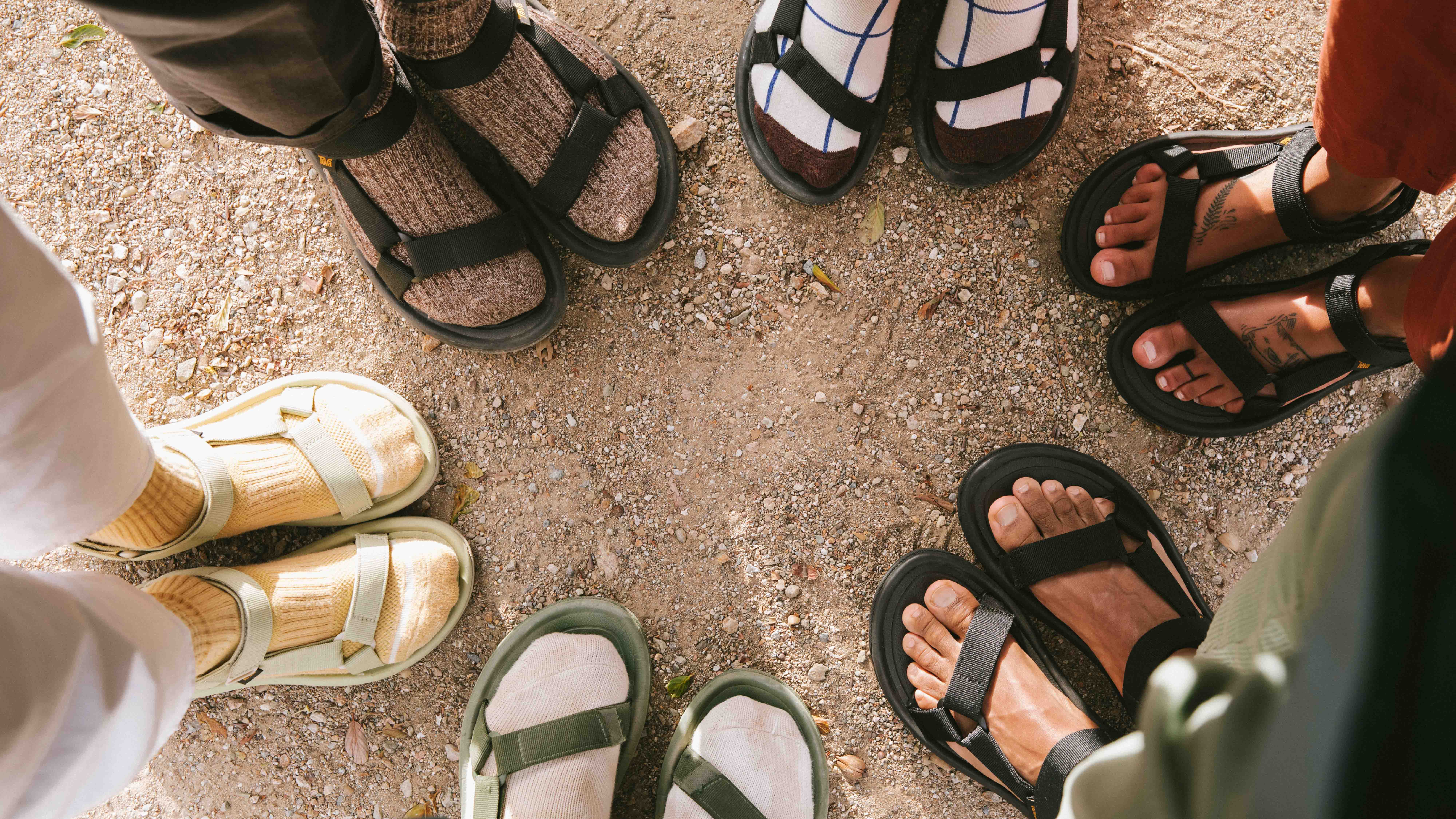close up of  people standing in circle wearing Teva Original sandals