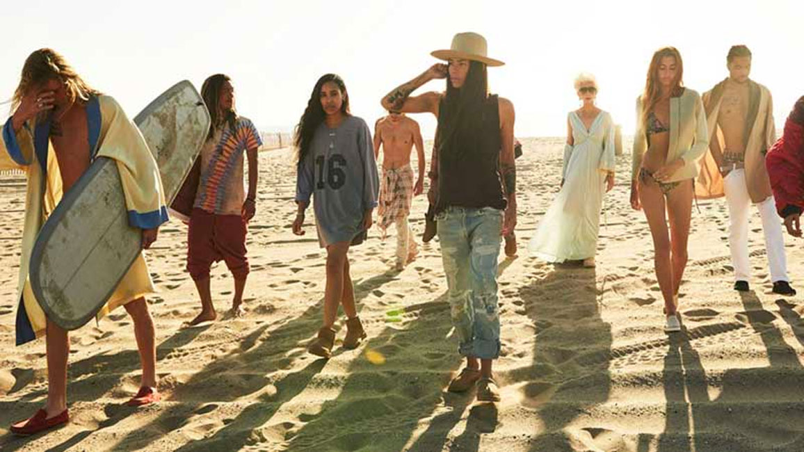 Large group walking on beach in UGG shoes.