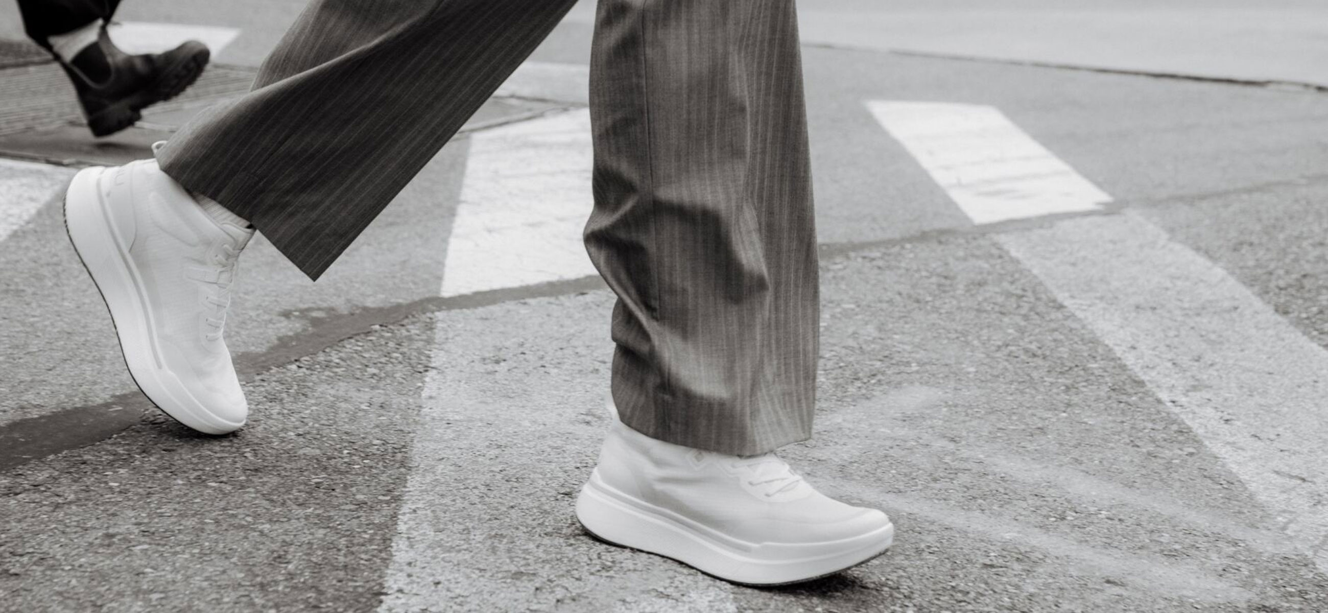 Close up of persons legs walking across a street wearing Ahnu shoes.